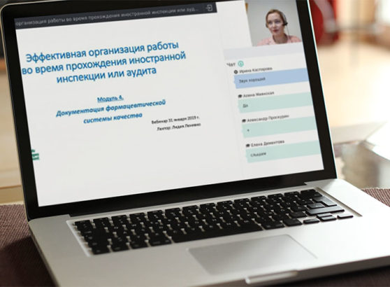 Un ordenador portátil abierto sobre una mesa de oficina que muestra la interfaz de un seminario web técnico en ruso titulado 'Organización eficaz del trabajo durante una inspección o auditoría extranjera. Módulo 4: Documentación del sistema de calidad farmacéutica', con una miniatura de vídeo en directo de la ponente Lidia Lianiuka Lenivko.